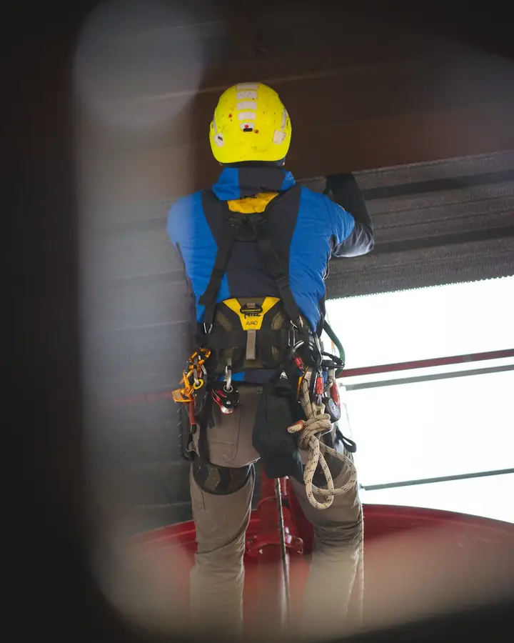Worker in a hard hat and full fall-protection harness